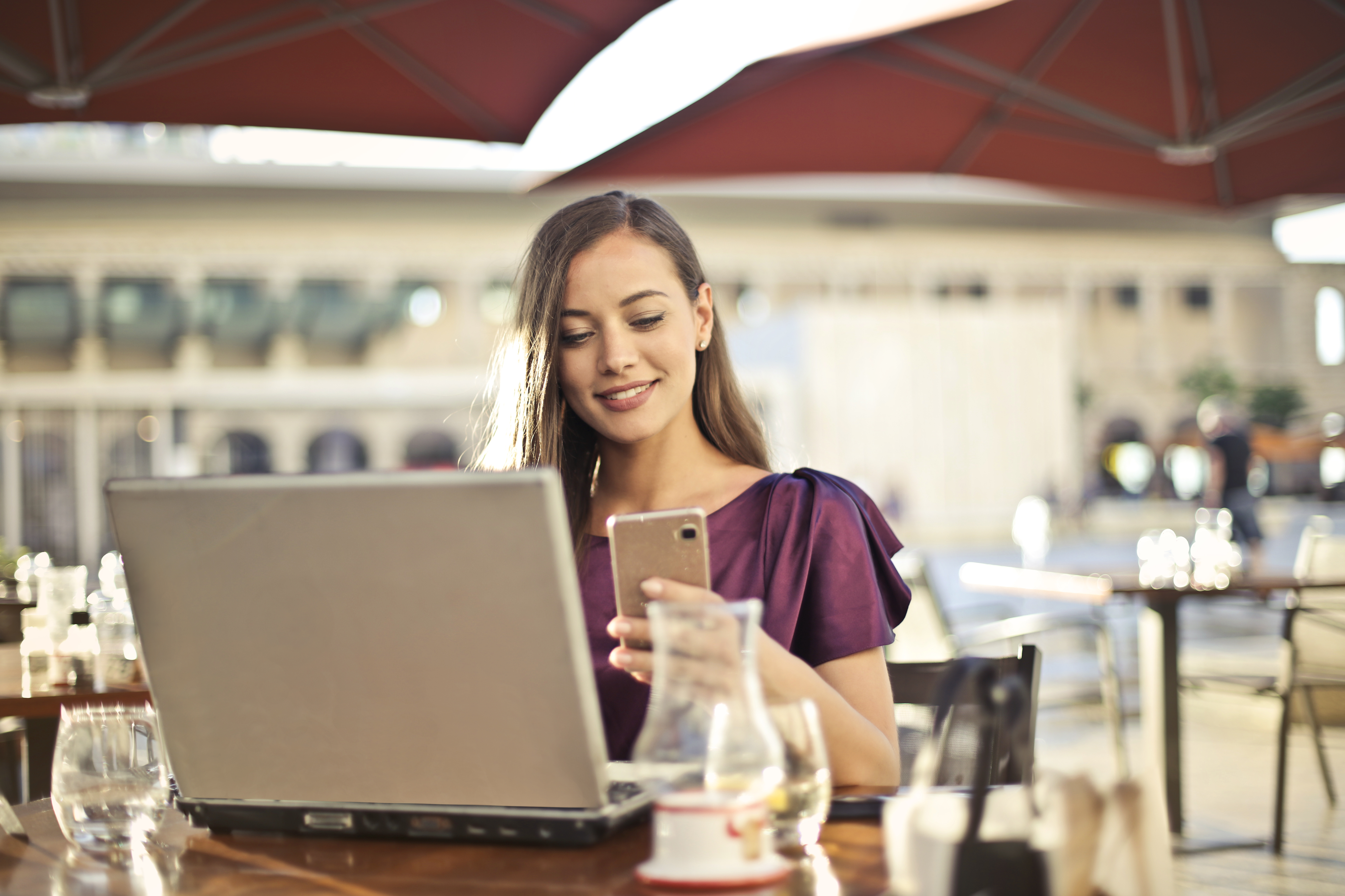 woman-wearing-purple-shirt-holding-smartphone-white-sitting-826349.jpg